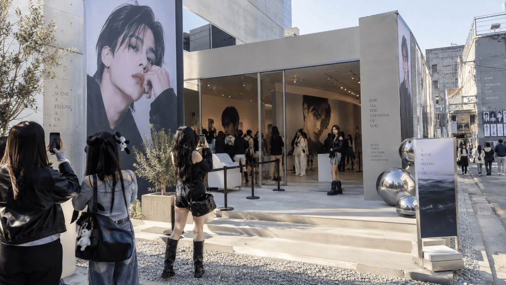 Exterior view of an art exhibit featuring large portraits and visitors taking photos in front of the building.