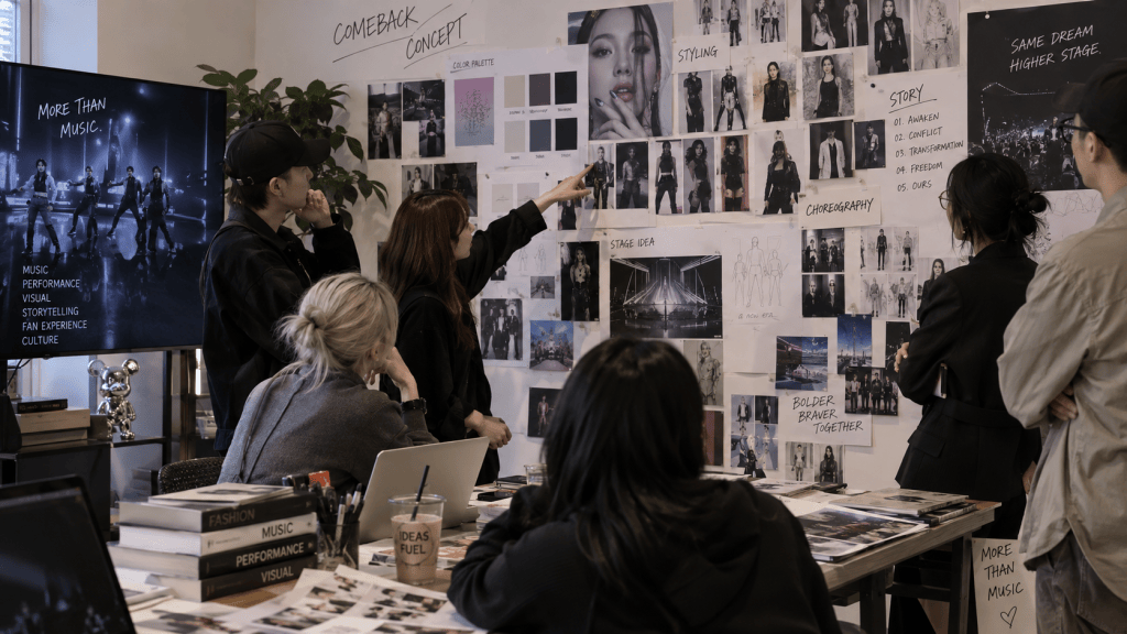A creative team brainstorming in a modern office, reviewing visual concepts and ideas for a music comeback on a wall covered with photos, sketches, and color palettes.